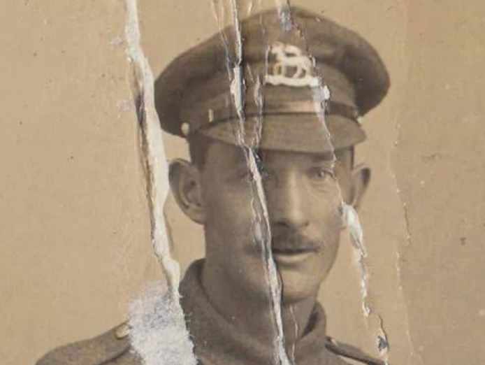 Torn sepia portrait of a WWI soldier with cracks running through his face